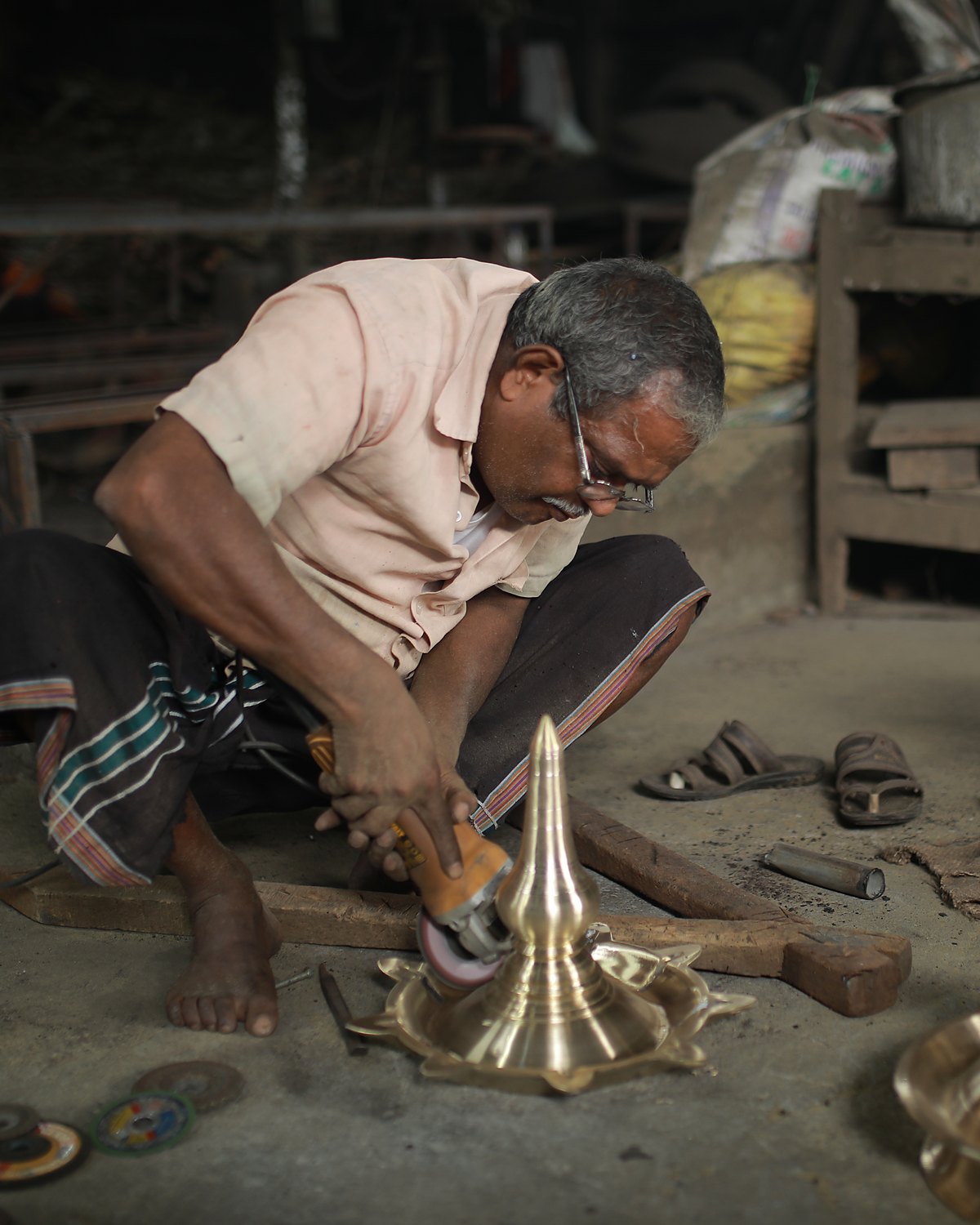 A craftsman hand-finishing a lamp at the workshop